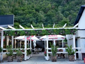 ein Gebäude mit Pflanzen, Tischen und Sonnenschirmen in der Unterkunft Defileu in Bumbeşti-Jiu