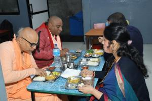 a group of people sitting around a table eating food at Sri Chaitanya Saraswat Math in Krishnanagar