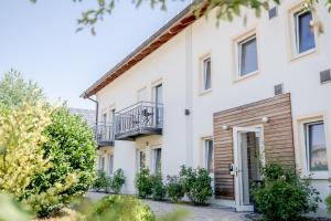 a white house with a balcony and trees at Hotel Donau-Ries in Mertingen