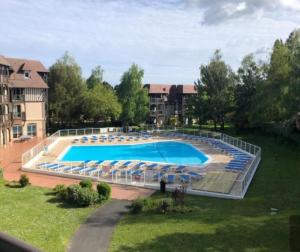 a large swimming pool with blue chairs in a yard at Zipporah in Deauville