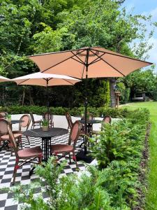 Un patio con mesas y sillas con sombrilla. en Villa V Petit Hôtel, en Valkenburg