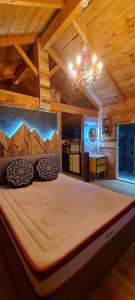 Cama grande en habitación con lámpara de araña en Le Masdemoiselle Chalet, en Salernes