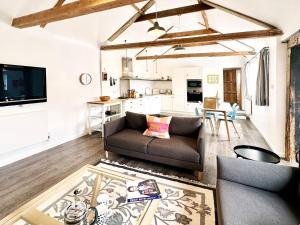 a living room with a couch and a kitchen at Bertie by The Suffolk Cottage Collection in Chillesford