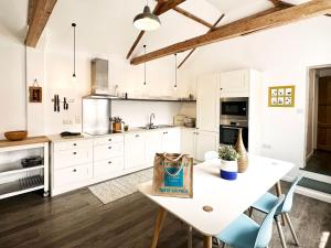 a kitchen with white cabinets and a table with a bag on it at Bertie by The Suffolk Cottage Collection in Chillesford