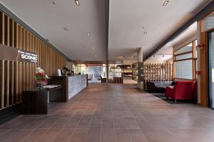 a lobby of a hotel with red chairs and a counter at Scenic Hotel Franz Josef Glacier in Franz Josef