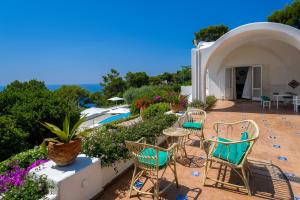 a patio with chairs and tables and a pool at Il Carrubo Capri in Anacapri