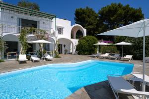 a pool with chairs and umbrellas next to a house at Il Carrubo Capri in Anacapri