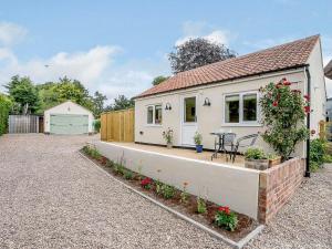 a white house with a table in a driveway at Wit's End Holiday Cottage in Woodhall Spa