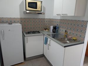 a kitchen with white cabinets and a microwave and a sink at Le nid cosy in Tabarka +8 photos