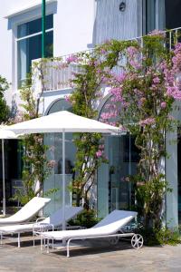 a row of lounge chairs and umbrellas in front of a building at Il Carrubo Capri in Anacapri