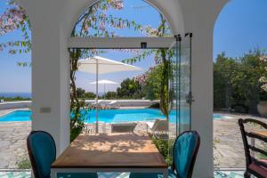 a room with a table and a view of a swimming pool at Il Carrubo Capri in Anacapri +37 photos