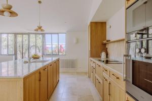 een grote keuken met houten kasten en een groot raam bij Villa Rhétaise - Loix in Loix