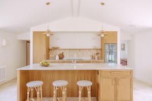 een keuken met een eiland met drie krukken bij Villa Rhétaise - Loix in Loix