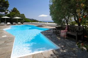 a blue swimming pool with a bench and umbrella at Il Carrubo Capri in Anacapri