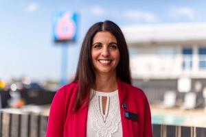 a woman wearing a red jacket smiles at the camera at Motel 6 Pasadena, CA Old Town Pasadena Area in Pasadena