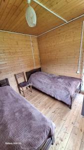 two beds in a room with a wooden wall at Cottage Keleri in Mazeri +8 photos