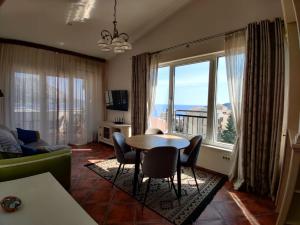 a living room with a table and chairs and a large window at Lux M & A Apartments in Budva
