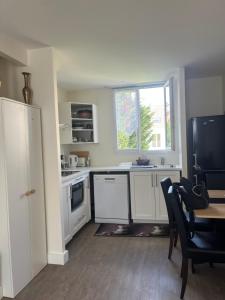 a kitchen with white cabinets and a table and a window at Maisoncat in Mézières-sur-Seine