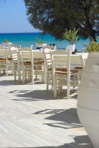 una fila di tavoli e sedie bianchi sulla spiaggia di Galatis Beach Hotel ad Aliki