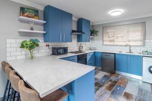 Una cocina con gabinetes azules y una encimera. en Equanimity - Stylish 4 sleeper - Wilderness Centre, en Wilderness