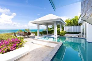 a swimming pool with a gazebo and the ocean at Villa Coral Turks Caicos in Turtle Cove