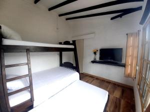 a bedroom with a bunk bed and a television at Finca Villa del pilar, casa campestre con vista a las montañas in Pereira
