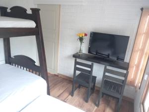 a bedroom with a desk with a tv and a bed at Finca Villa del pilar, casa campestre con vista a las montañas in Pereira