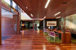un vestíbulo de oficina con suelo de madera y sillas moradas en Te Waonui Forest Retreat, en Franz Josef