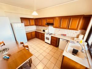 a kitchen with wooden cabinets and a table and a refrigerator at Blue Pearl Chios apartment in Chios