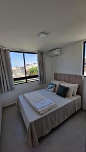 a bedroom with a large bed with two windows at Apartment in Praia de Formosa in Cabedelo