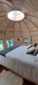 une chambre avec un grand lit dans une pièce en bois dans l'établissement Les cottages de Sarrant, à Sarrant