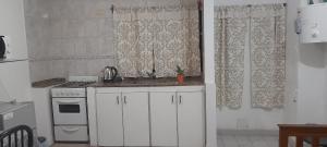 een keuken met witte kasten, een fornuis en gordijnen bij Amador Lucero apart II in San Miguel de Tucumán