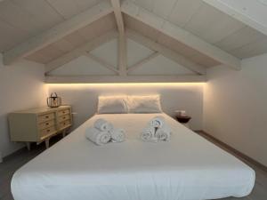 una camera da letto con un grande letto bianco con due asciugamani di Two houses and an arch - Ariadne and Aristeidis apartments a Rethymno