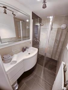 ein weißes Badezimmer mit Waschbecken und Dusche in der Unterkunft Ferienwohnung Flir in Jerzens