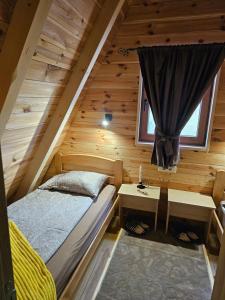 a bedroom in a log cabin with a bed and a window at Malii Rajj Žabljak in Žabljak