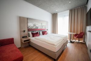 Un dormitorio con una cama grande y una silla roja. en Das Wasserburg Hotel, en Wasserburg am Inn