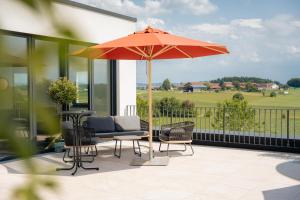 a patio with a table and an umbrella at Das Wasserburg Hotel in Wasserburg am Inn
