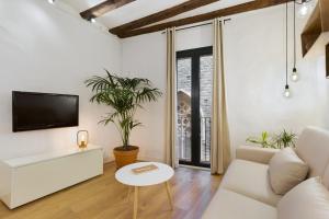 een woonkamer met een witte bank en een tv bij Ola Living Born in Barcelona