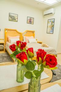 una camera da letto con due vasi di rose su un tavolo di Sobe Teatar 3 a Subotica