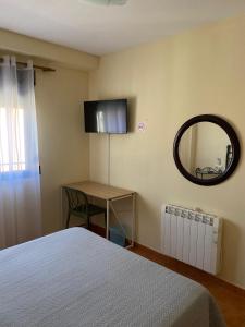 Un dormitorio con una cama, una mesa y un espejo. en Pensión Dani, en Casinos