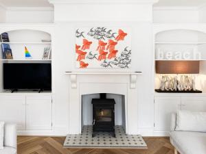 ein Wohnzimmer mit Kamin und Fernseher in der Unterkunft Lighthouse View by The Suffolk Cottage Collection in Southwold