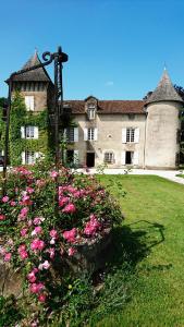 un grand bâtiment avec des fleurs roses devant lui dans l'établissement Pierre Deluen Domaine de la Grange de Quaire, à Chassenon