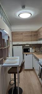 a kitchen with white appliances and a table with a chair at Emily Apartman Salgótarján in Salgótarján