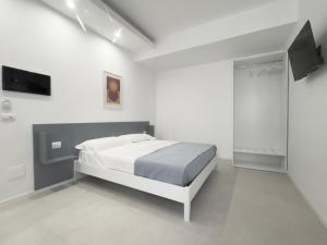 a white bedroom with a bed and a tv at Fata Morgana Guest Rooms in Diamante