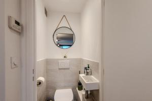 une salle de bain blanche avec un lavabo et un miroir dans l'établissement À quelques pas du Lac Leman, à Évian-les-Bains 15 autres photos