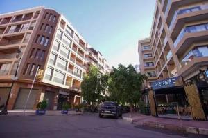 una calle en una ciudad con edificios altos y un coche en Charming Cozy 2 Bedrooms central Gueliz, en Marrakech