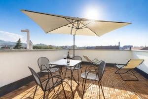 a table and chairs on a balcony with an umbrella at Alba Palace Luxury Apartments in Alba