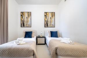 a room with three beds with towels on them at Luxury Two Bedroom Apartment with City & Pool View by Delujo Stays in Dubai