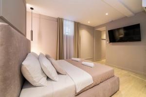 a bedroom with a bed with white pillows and a television at Good Grace Apartments in Zagreb