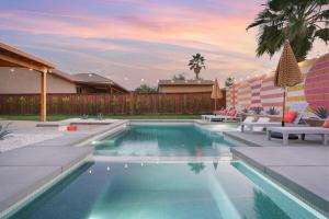 a swimming pool in a backyard with chairs and a fence at Colorful house with Amazing Backyard in Coachella